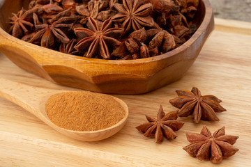 Star anise and powder in wooden spoon isolated on wooden background.