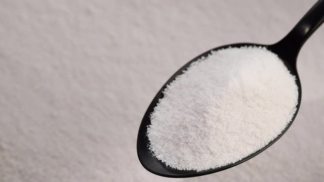 collagen powder in black spoon and collagen powder background rotating. Natural beauty and health supplement top view