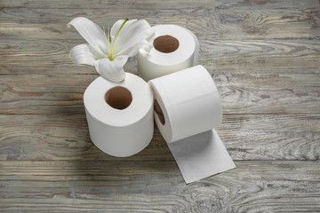 Rolls of toilet paper and flower on wooden background