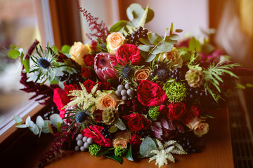 Obraz na płótnie Canvas Wedding. The bride's bouquet. Wedding bouquet . A bouquet of red flowers, black berries and greens lying near the window