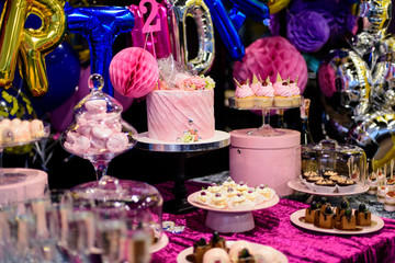 Pink birthday cake and sweets on the candy bar