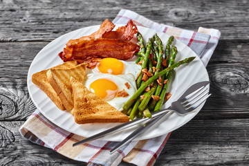 fried eggs, bacon, toast, asparagus on a plate