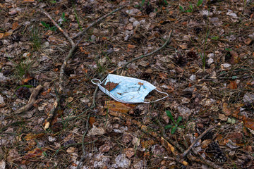 a medical mask thrown out in the woods. Medical waste related to the COVID-19 epidemic. Threat to people and nature.