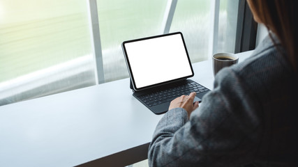 Mockup image of a woman using and typing on tablet keyboard with blank white desktop screen as computer pc , coffee cup on the table