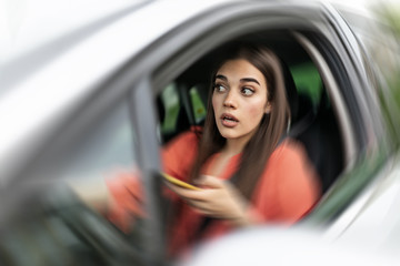 Texting and driving, behind the wheel. Breaking the law. Woman driving car distracted by her mobile...