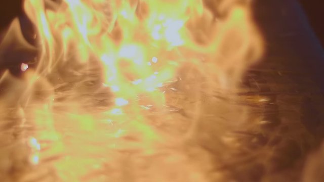 A blue wave of fire diverges from the center with the formation of a large flame and bright sparks on a shiny surface. Macro. Closeup. Slow mo, slo mo, slow motion, high speed camera. V-log - High Dyn