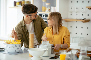 Young couple making delicious food at home. Loving couple enjoying in kitchen..	