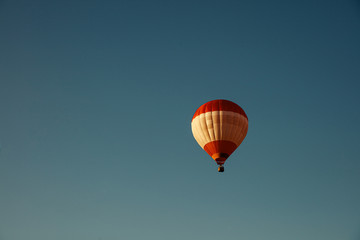 Colorful hot air balloon with basket flying high in blue sky. Natural background and wallpaper. Concept of adventure.