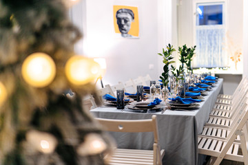 Christmas table with beautiful decoration in white and blue colors. Professional serving for celebration family holiday. Festive details.