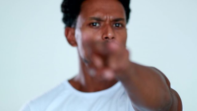 Disapproving African american man signaling watching you with finger and eye, rejecting with finger
