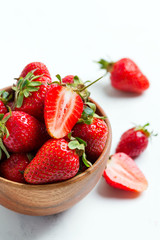Wooden bowl with fresh natural ripe juicy red strawberry fruits on a white background.