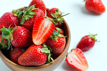 Wooden bowl with fresh natural ripe juicy red strawberry fruits on a white background.