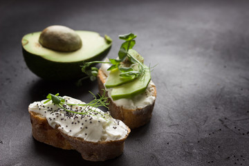 Healthy sandwiches with avocado , cream cheese and micro green. Vegan sandwiches, vegan food, healthy eating. Template with space for text , black background