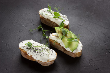 Healthy sandwiches with avocado , cream cheese and micro green. Vegan sandwiches, vegan food, healthy eating. Template with space for text , black background