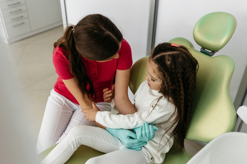 A cute little girl at the dentist's office talking to her pediat