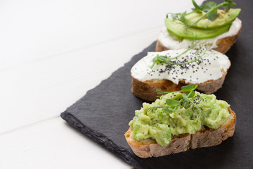 Healthy sandwiches with avocado , cream cheese and micro green. Vegan sandwiches, vegan food, healthy eating. Template with space for text , black  and white background