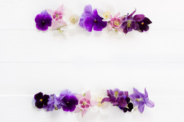 Fototapeta na wymiar Flowers flat design. Floral frame violet , purple, pink white flowers. Template with copy space on white wooden board. Viola , Aquilegia, Anemone flowers