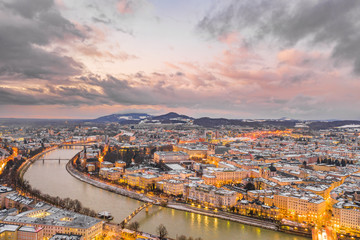 Fototapeta premium Aerial drone view of north Salzburg and mirabelle park by Salzach river in snowy winter during sunset hour