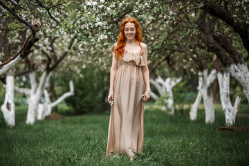 red-haired girl in a blooming garden