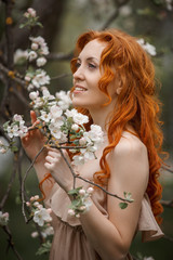 Naklejka premium red-haired girl in a beige dress in the garden
