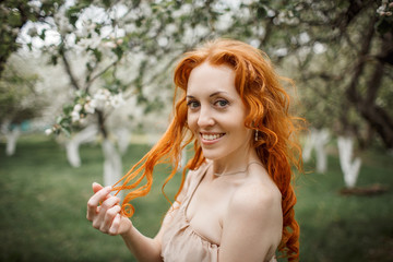 Fototapeta premium red-haired girl in a beige dress in the garden