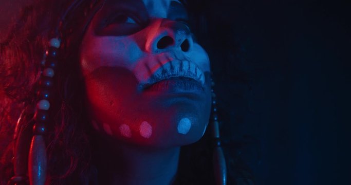 Portrait of a tribal shaman in red and blue lighting, looking around, 4k