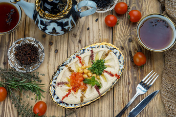 Chickpea hummus in plate on wooden table