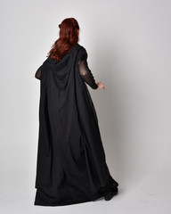 fantasy portrait of a woman wearing long black cloak. Full length standing pose  with back to the...