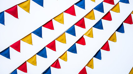 triangle flag and Flags of various colors, lined up hanging on a white back