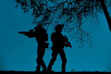 The silhouette of military soldier with weapons at night ,servey and careful around holding gun,...