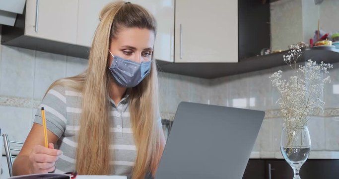 woman in gray mask works in laptop and looks at the camera shows thumb up gesture slow motion