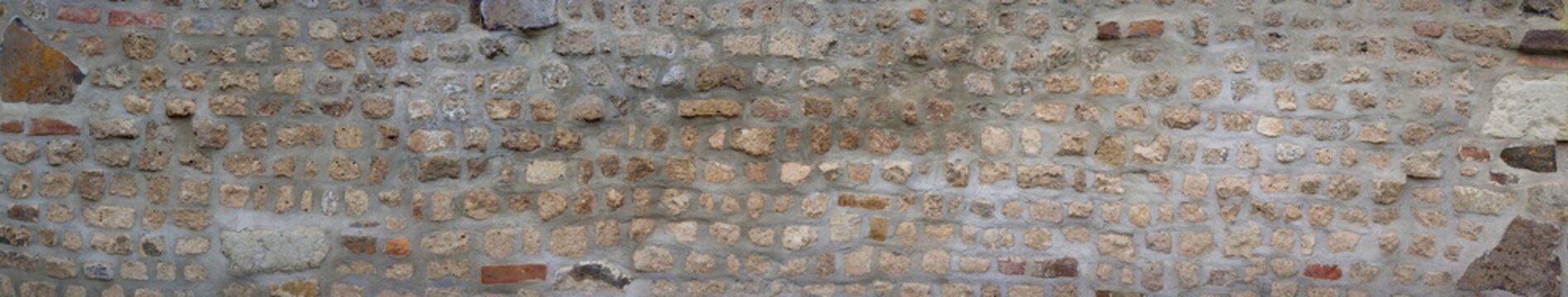 Very old middle-aged wall. Stone wall made of bricks and various stones.