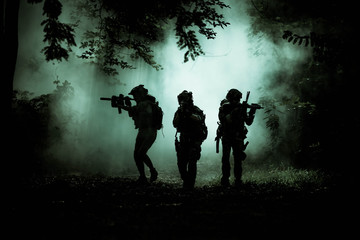 Fototapeta na wymiar The action soldiers walking hold weapons with smoke light at night time background.
