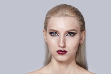Portrait of a blonde with bright eye and lip makeup. A look into the camera.