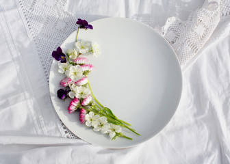 empty white plate with spring flowers on a white background.