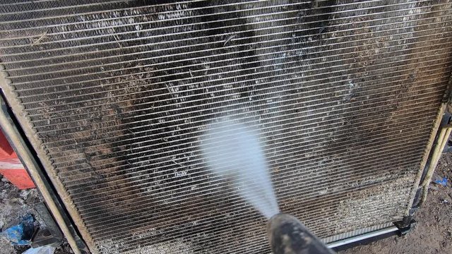 Pressure washer cleaning a dirty radiator