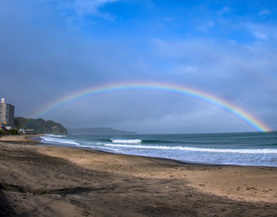 A stunning full rainbow in a blue sky above the beach of Hebara in Chiba, Japan there are nice clean waves breaking that are good for surfing. The beach is famous for surfing In Japan.