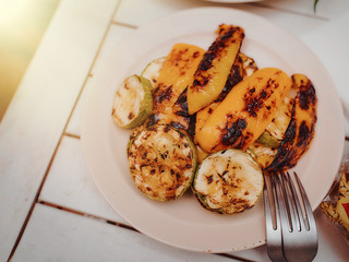 Vegetables for grilling tomatoes and mushrooms on a white plate with spoonsun flare