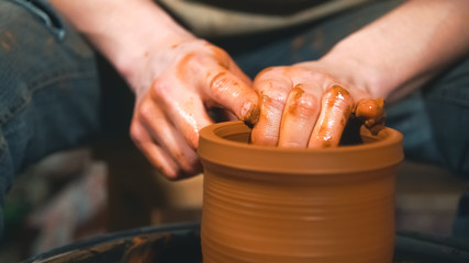 Potter works with clay on wheel in workshop.