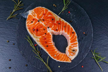 Raw salmon steak with spices on black slate. Top view