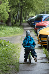 Little boy rolling on a runbike on the sidewalk