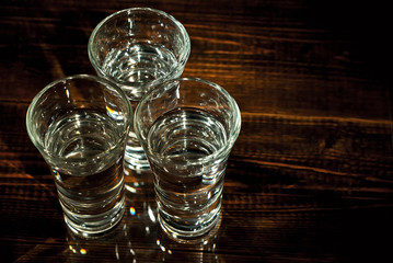 Glasses with alcohol close up. Vodka on a brown wooden background. Glass table from worn shabby boards.