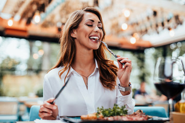 Young beautiful and happy woman enjoying in delicious meal in luxurious restaurant.