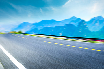 Motion blurred asphalt road and green mountain,road ground background.