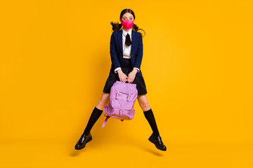 Full length photo of high school teenager girl jump hold backpack bag wear black blazer jacket long socks skirt medical mask isolated over bright shine color background