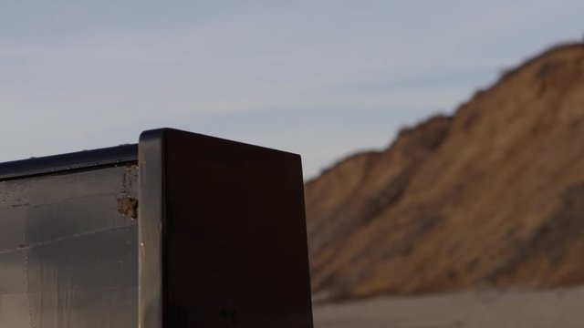 Man on the beach pours old piano gasoline from a metal canister, prepares to set fire. art scene