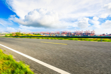 Motion blurred asphalt road and container port terminal landscape under blue sky.