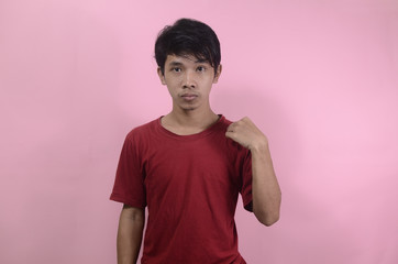 Young asian man standing up. Asian men wearing red t shirts isolated on a pink background
