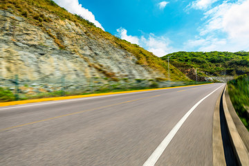 Motion blurred asphalt road and green mountain,road ground background.
