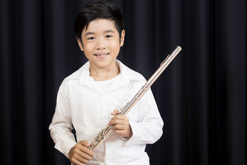 Portrait of a cute Asian elementary school boy wearing a jeans and a white shirt with a flute